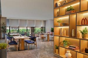 雅加达PARKROYAL Serviced Suites Jakarta的一间带桌椅和架子的餐厅