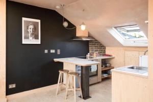 伦敦Stunning studio loft in Brixton, London的厨房设有黑色的墙壁、桌子和凳子
