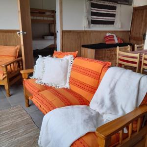 百内三塔CABAÑA ESTANCIA LAZO的客厅配有带枕头的橙色沙发