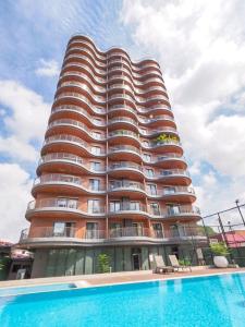 阿克拉Intimate Studio Apartment - Mirage Residence的一座高大的建筑,前面有一个游泳池