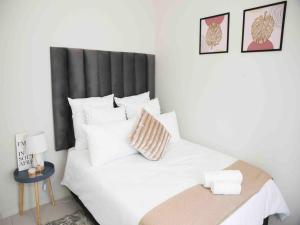 米德兰Midrand Cosy & Stylish Haven的一张带黑色床头板和白色枕头的白色床