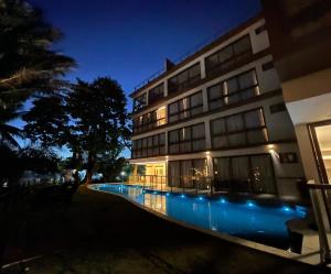瓜拉久巴Guarajuba Suítes Premium Boutique Hotel的一座晚上设有游泳池的建筑