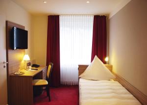 绍尔滕斯慕尼奈克酒店的配有一张床、一张书桌和一扇窗户的酒店客房