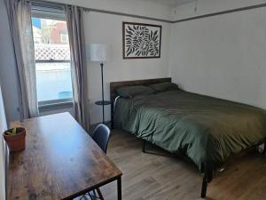 长滩Entire home in Historic Long Beach close to shops的一间卧室配有一张床、一张桌子和一个窗户。