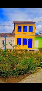 穆库热Hostel do Coreto的院子里的黄色房子,有蓝色的窗户