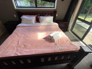 汉密尔顿Self checkin master room with private bathroom的一张带粉红色棉被的床和两条毛巾