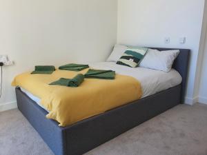 伦敦Cozy Room with Private Bathroom in Luxurious Flat的一张黄色毯子和绿色枕头的床