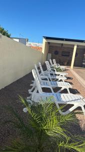 里韦拉Casa con piscina y barbacoa的坐在大楼顶上的一排白色草坪椅