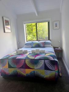 奥克兰The Partchery Devonport的一间卧室配有一张带五颜六色的被子的床和窗户