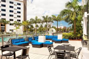 迈阿密雅乐轩迈阿密多拉酒店的庭院里设有蓝色的桌椅,棕榈树
