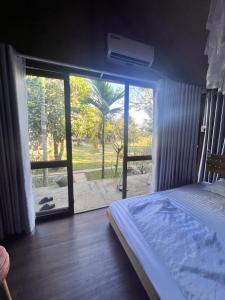 Buôn Kô M'lêoKomleo Farm的一间卧室设有一张床和一个滑动玻璃门