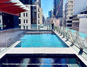 悉尼Sydney Cosmopolitan CBD Apartment的站在带游泳池的大楼顶端的人