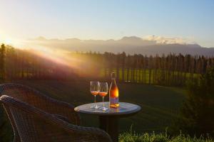 伦威克Luxury cottage with stunning vineyard views的桌子上放有一瓶葡萄酒和两杯酒