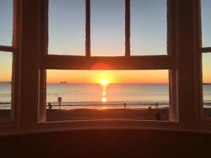 韦茅斯白色悬崖宾馆的日落时分享有海滩美景的窗户