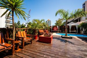 埃斯特角城32旅馆 的一个带椅子和棕榈树的甲板以及游泳池