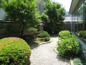 泉佐野關西機場美景花園飯店的一座花园,在房子前面有灌木和鲜花