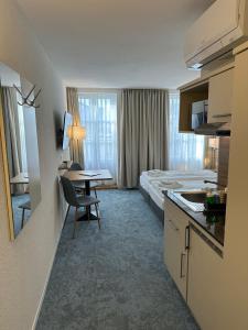 因特拉肯Aparthotel Krone - Self Check-In的酒店客房设有一张床、一间厨房和一张书桌