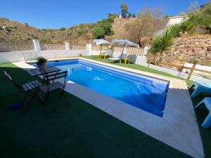 马拉加Casa Rural Los Almendros的游泳池旁设有桌椅