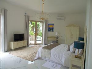 Jasmine Bay Hotel & Spa的一间白色卧室,配有床和电视
