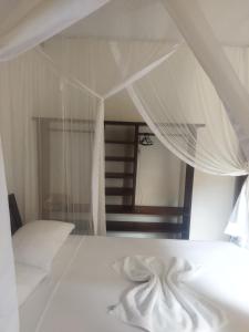 托兰克索Casa da Drica Trancoso的一间卧室配有一张带白色床单和镜子的床