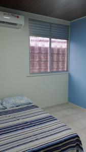 马瑙斯UM POUCO DE NATUREZA NO LAR的一间卧室设有一张床和两个窗户。