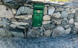 Ó MéithMaggie janes cottage Carlingford omealth的石墙上的绿色邮局盒子