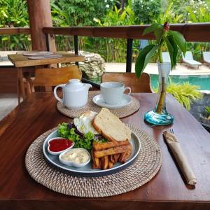 卡朗阿森Sunrise Paradise Bali的一张桌子,上面放着一盘食物,上面放着三明治和薯条