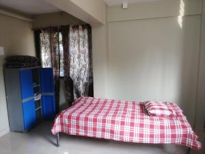 拉特纳吉里Samarth Homestay的一间卧室配有一张带 ⁇ 子毯子的床