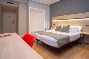 萨拉戈萨AZ Hotel El Príncipe的一间卧室配有一张大床和一张红色椅子