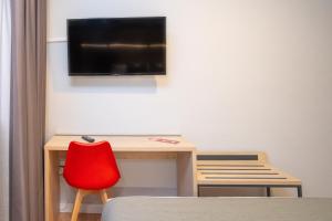 萨拉戈萨AZ Hotel El Príncipe的一张带红色椅子的桌子和墙上的电视