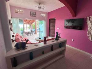 锡瓦塔塔内霍Casa Mana: Beachfront Home w/pool on Playa Blanca的客厅设有粉红色的墙壁和一张雕像桌子