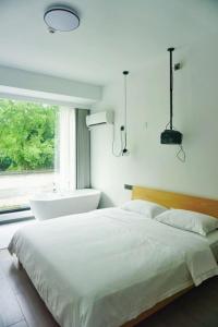 桐乡乌镇西栅禾桃民宿的一间卧室设有一张床、浴缸和一个窗口