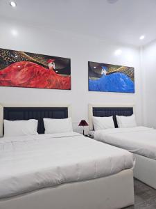 海阳Milano Hotel的墙上有两幅画作的房间的两张床