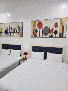 海阳Milano Hotel的卧室内的两张床,墙上挂有绘画作品
