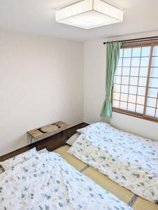 Shikyū1棟貸 白老 登別 癒やしの宿 源泉掛け流し温泉 hokkaido noboribetsu shiraoi的一间卧室设有两张床和窗户。