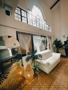 大雅台Sky Rancho Hostel的客厅配有白色沙发和棕榈树