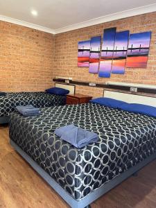 Coonamble库南布尔汽车旅馆的一间卧室设有一张大床和砖墙
