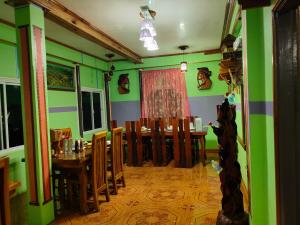 巴纳韦BANAUE EVERGREEN HOSTEL AND RESTAURANT的一间拥有绿色墙壁和桌椅的用餐室