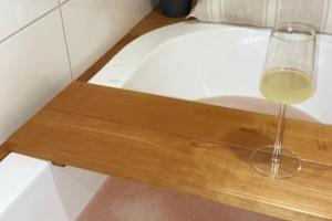 赫尔辛基Verso la casa mia的浴缸旁的木托盘上坐着一杯葡萄酒