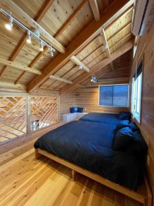 南房总市Blu Pointe的木制客房内的一间卧室配有一张大床