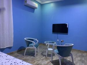 MiochoFamily & Friends Apartments的一间设有两把椅子和蓝色墙壁上电视的房间