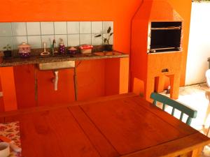 圣塞巴斯蒂安Pousada Sol do Araçá的厨房设有橙色墙壁和木桌