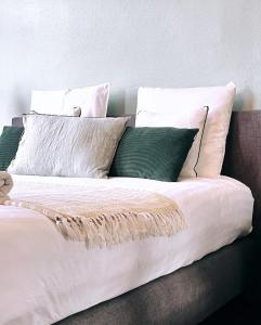 登德尔蒙德Domus Portus的一张带白色床单和绿色枕头的床