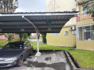 古晋Eden 8pax 3Rooms apartment near Kuching Airport的停车场的遮盖下停的汽车