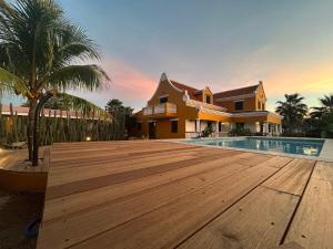 克拉伦代克Landhuis Belnem Bonaire的一座房子,设有木甲板,毗邻一个游泳池