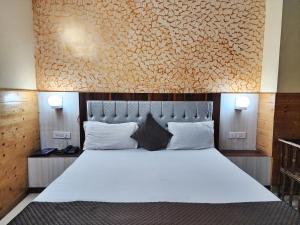 西姆拉Hotel Taj Palace near Mall Road的卧室配有一张白色大床和一堵墙