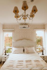 弗洛里亚诺波利斯Pousada Paty´s Garden的一间卧室配有一张带吊灯的床和两个窗户。