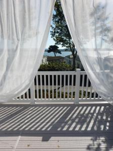 浦耳Family Seaside Retreat Private Stay at 5-Star Rockley Holiday Park Poole的门廊上的白色围栏和白色窗帘