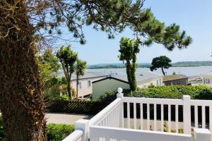 浦耳Family Seaside Retreat Private Stay at 5-Star Rockley Holiday Park Poole的白色的门廊,有白色的栅栏和一棵树