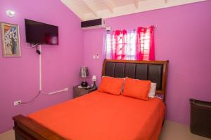 圣安斯贝Ocho Rios Drax Hall 1 Bedroom sleeps 1-3 persons的一间卧室设有紫色的墙壁和一张带橙色枕头的床